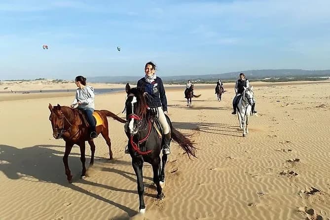Horse riding on Taghazout beach at sunset with riders silhouetted against the Atlantic ocean